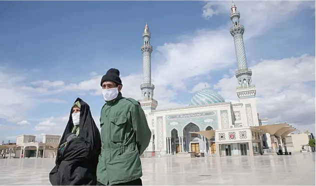  ?? Reuters ?? ↑
A couple wearing protective facemasks walks on the street in Qom, recently.