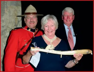  ??  ?? Gretchen and Donald Ross, with Constable Terry Russell, accept a carved usuaq at the 2017 Walrus Gala.