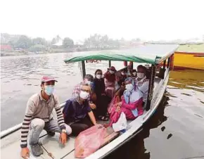  ?? [Foto L Manimaran/bh] ?? Pengusaha perahu tambang dan penumpang memakai topeng hidung dan mulut ekoran jerebu dengan bacaan IPU 225 di Sungai Sarawak, Kuching, semalam.