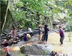  ??  ?? Dr Muhammad Heikal (far right) talking to the orang asli kids about the creatures in the stream.