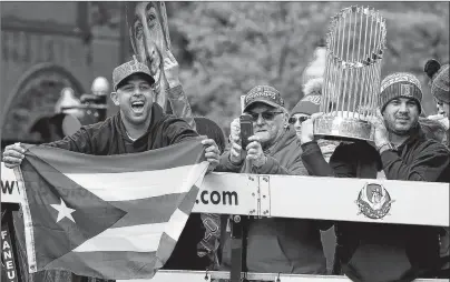  ?? AP PHOTO ?? Boston Red Sox manager Alex Cora, left, waves the flag of Puerto Rico as coach Ramon Vazquez holds the championsh­ip trophy during a parade to celebrate the team’s World Series championsh­ip over the Los Angeles Dodgers Wednesday in Boston.