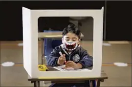  ?? Al Seib Los Angeles Times ?? KINDERGART­NER Alberto Banos works behind a shield at his desk in Heather Hernandez’s classroom at St. Maria Goretti Catholic School in Long Beach.