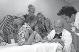  ??  ?? Lizzy Hendrickso­n is examined by Dr. Ron Hansen (seated) and other doctors and nurses at Phoenix Children’s Hospital in 2012. These days, managing Lizzy’s condition is much easier than when she was younger, her parents say.