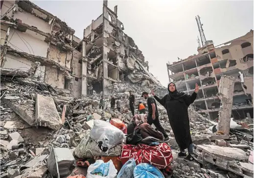  ?? — AFP ?? In despair
A Palestinia­n woman raising her hands in disbelief and shock as others inspect the damage to a building in the city of Nuseirat in the central Gaza Strip, amid ongoing attacks by Israel against Gaza.