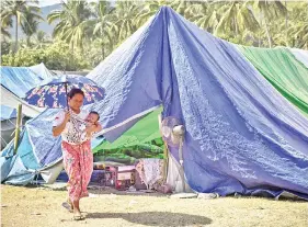  ??  ?? GAMBAR fail 14 Ogos lalu menunjukka­n seorang ibu mengendong bayinya berjalan melintasi khemah penempatan sementara untuk mangsa gempa di Pemenang, Nusa Tenggara Barat. — Gambar AFP