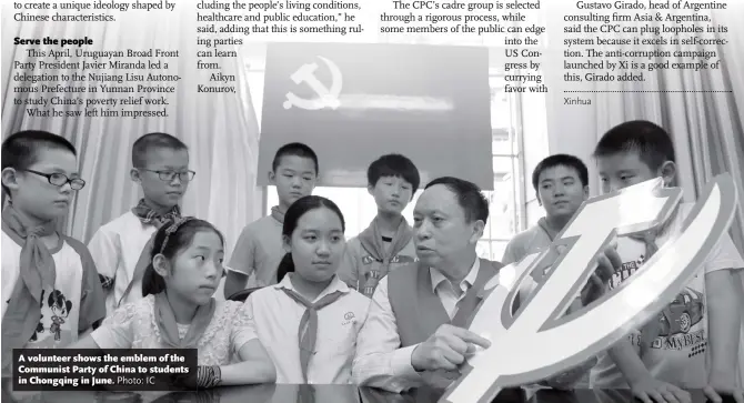  ?? Photo: IC ?? A volunteer shows the emblem of the Communist Party of China to students in Chongqing in June.