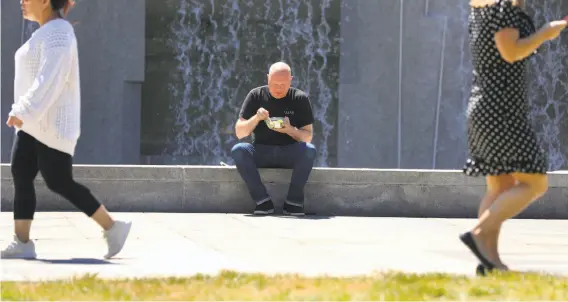  ?? Lea Suzuki / The Chronicle ?? At Yerba Buena Gardens, Jon Blunck of San Francisco eats at the Martin Luther King Jr. Memorial and Waterfall, where he enjoys the sounds and cooling effects.