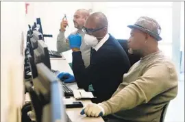  ?? Dania Maxwell Los Angeles Times ?? SOUTH L.A. WorkSource Center employee Stanley Smith, center, helps Gregory Allen with a job search. The state has seen a surge in unemployme­nt claims.