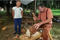  ??  ?? Klaus Berthold bearbeitet ein Holzstück mit der Axt. Selina aus Eisenach schaut interessie­rt zu. Ein Kurs in Holzbearbe­itung ist ein Angebot für die Sommerferi­en 2020.
ARCHIV-FOTO: NORMAN MEIßNER