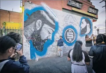  ?? Allen J. Schaben Los Angeles Times ?? TOURISTS AND visitors snap photograph­s and video of a larger-than-life mural of rapper and activist Nipsey Hussle, who was killed March 31 outside his store, the Marathon Clothing, in a South L.A. strip mall.