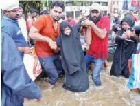  ?? Reuters ?? Rescuers help a woman to move through a water-logged road after she was evacuated from a flooded area in Aluva on Saturday.