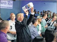  ?? AP PHOTO ?? U.S. President Donald Trump tosses paper towels into a crowd as he hands out supplies at Calvary Chapel, Tuesday, in Guaynabo, Puerto Rico.