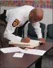  ?? STAFF PHOTO BY ANDREW RICHARDSON ?? Charles County Sheriff Troy Berry signs his name after being sworn in as the Southern Maryland representa­tive of the Maryland Police Training and Standards Commission.