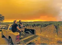  ?? ASSOCIATED PRESS FILE PHOTO ?? Thomas Henney, right, and Charles Chavira watch a plume spread over Healdsburg, Calif., in August as the LNU Lightning Complex fires burn. Smoke from the West Coast wildfires has tainted grapes in some of the nation’s most celebrated wine regions.