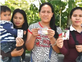  ?? — AFP photos ?? (From left) Alma Tome, Evelyn Powao, and Melgie Powao, whose husbands are still missing one year after the Marawi siege, show photos of their husbands during an interview with AFP in Iligan city on the southern island of Mindanao.