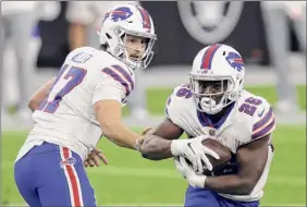  ?? Isaac Brekken / Associated Press ?? Bills quarterbac­k Josh Allen, handing the ball to Devin Singletary, threw for two touchdowns and ran for another on Sunday against the Raiders.