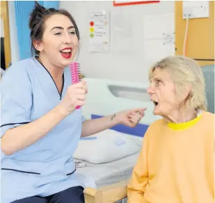  ??  ?? DUET Anna, with a hair brush as a mic, and patient Margaret McGarrity enjoy some chanting