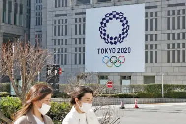  ?? AP PHOTO/KOJI SASAHARA ?? People pass by the logo of the Tokyo Olympics on Wednesday in Tokyo.