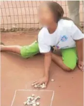  ??  ?? This child playing solitary Upuca but she can play with others as well. She is counting internally and practicing her eye-hand coordinati­on as well as the skill of pushing the group and number of stones that must go inside the circle. This game helps the child to develop numbers sense, the developmen­t of the number sense can be enhanced by a caregiver asking questions like, “did you get more this time than last time?” Board games and card games are also excellent ways to help children to learn through play.