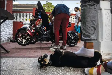  ?? ?? Kiera gets a foot rub at his home by his caretaker as people work on their electric scooters in Cojimar after attending a gathering in the capital for stunts and races.