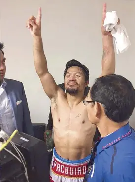  ??  ?? Pacquiao celebrates in the locker room as assistant trainer Dodong Donaire (right) looks on.