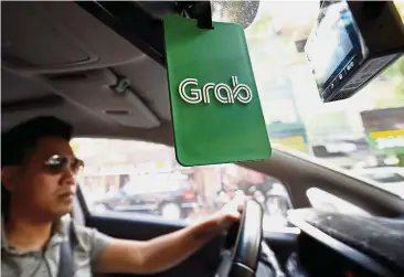  ??  ?? Essential software: A Grab taxi drives on a street in Hanoi, Vietnam. Super Apps have become integral to big cities, with their dense population­s and intense commercial activity. — Reuters