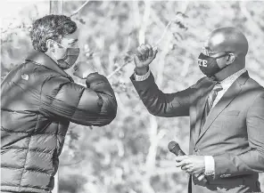  ?? MICHAEL HOLAHAN/ USA TODAY NETWORK ?? Democratic candidates Jon Ossoff, left, and Raphael Warnock exchange elbow bumps during a rally in Augusta, Ga., on Monday. They are challengin­g incumbent Republican­s in a runoff Tuesday.