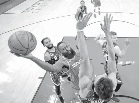  ?? ASSOCIATED PRESS ?? Houston Rockets' James Harden, center, shoots as San Antonio Spurs' Derrick White, bottom, defends during the second half of an NBA basketball game in Houston.