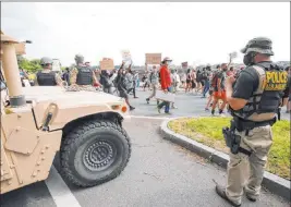  ?? Alex Brandon The Associated Press ?? National Guard troops and other law enforcemen­t personnel watch protesters along Independen­ce Avenue in Washington on Saturday. A Guard spokeswoma­n said some members have tested positive for COVID-19 in the wake of the mass protests.