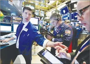  ?? AP PHOTO ?? Specialist Thomas McArdle, left, works with traders John Panin, centre, and Jeffrey Vazquez on the floor of the New York Stock Exchange. U.S. stocks skidded Monday morning after China raised import duties on U.S. pork, apples and other products.