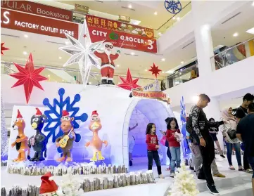  ??  ?? Children and the general public enjoying the Christmas decoration­s set up at Suria Sabah Shopping Mall.