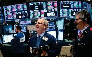  ?? — AFP ?? Traders and financial profession­als work on the floor of the New York Stock Exchange.