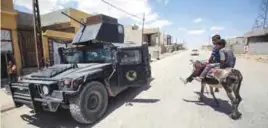  ?? —AFP ?? MOSUL: Boys ride a donkey as a humvee belonging to the Iraqi Counter Terrorism Service (ICTS) passes by while on patrol in the western neighborho­od of Tamuz in Mosul yesterday, after the area was retaken during the ongoing offensive against Islamic...