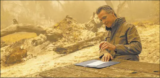  ?? Paul Kitagaki Jr. The Associated Press ?? California Gov. Gavin Newsom signs Assembly Bill 2147 after touring the North Complex Fire on Friday outside of Oroville, Calif.