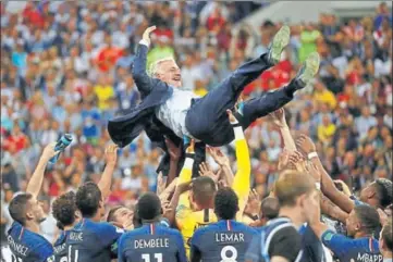  ?? REUTERS ?? Coach Didier Deschamps is thrown into the air by France players after their victory. (right) Samuel Umtiti kisses the trophy. ■