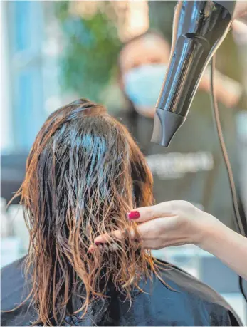  ?? FOTO: HARALD TITTEL/DPA ?? Friseurin Christina Helmling fönt in ihrem Friseurges­chäft im luxemburgi­schen Wasserbill­ig einer Kundin die Haare. Helmling profitiert vom Lockdown in Deutschlan­d und der Grenznähe, denn in Luxemburg dürfen Friseure unter strengen Auflagen Kunden bedienen.