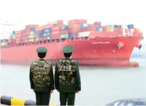  ?? AFP PHOTO ?? Chinese police officers watch a cargo ship at a port in Qingdao in China’s eastern Shandong province on March 8, 2018.