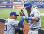  ?? Jim McIsaac / Getty Images ?? Dodgers manager Dave Roberts congratula­tes Justin Turner after his home run in the 11th inning.