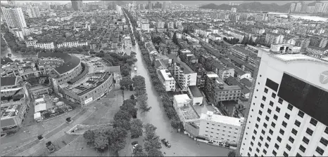  ?? SHAO HONGLONG / XINHUA ?? Top: Major streets in Linhai, Zhejiang province, are inundated by floodwater on Saturday after heavy rainstorms caused by Typhoon Lekima.