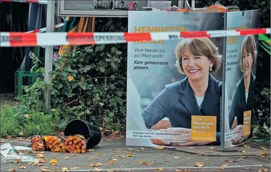  ?? FEDERICO GAMBARINI / AFP ?? Una galleda de flors bolcada al costat de cartells electorals de Henriette Reker, al lloc on ahir va ser atacada la candidata