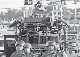  ??  ?? Tanks for everything: Ferguson, Mo., protests in 2014 led President Obama to limit police militariza­tion, which President Trump is set to reverse.
