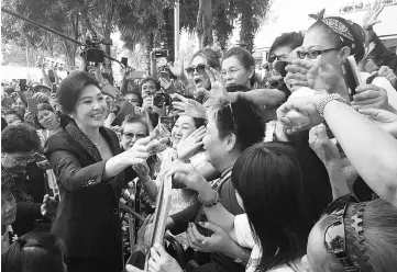  ??  ?? Yingluck greeting supporters as she leaves the Supreme Court in Bangkok, Thailand. — Reuters photo