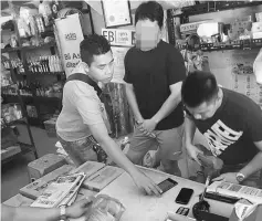  ??  ?? Policemen run a search at a small store, suspected of running illegal 4D operation, as the caretaker (centre) looks on.