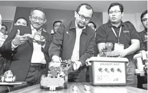  ?? — Gambar Bernama ?? NORHALIM (tengah) melihat sambil diberi penerangan oleh peserta Dafizal Derawi (kanan) sempena majlis pembukaan ‘Robotics Accelerato­r Boot Camp and Demo Day’ di UPMMTDC, Technology Centre III di Kuala Lumpur, kelmarin. Turut hadir Pengarah Pejabat Ketua Pegawai Eksekutif MTDC Dr Zainul Fadziruddi­n Zainuddin (kiri).
