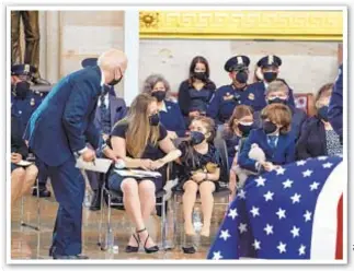  ??  ?? President Biden picks up dropped toy Capitol dome for Abigail Evans, 7, at memorial for her dad, slain Capitol Police Officer William “Billy” Evans, as her family looks on Tuesday.