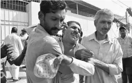  ?? SHAKIL ADIL/AP ?? People comfort a family member of a police officer killed during a shootout Friday at the Chinese Consulate in Karachi, Pakistan. Three attackers also were killed, officials said.