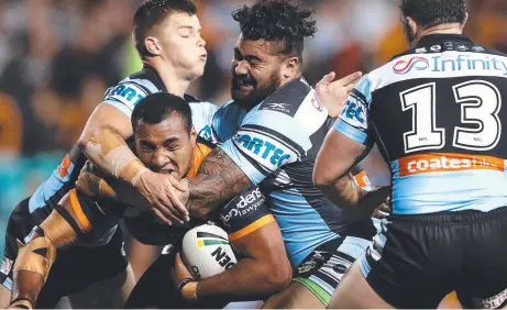  ?? Picture: GETTY ?? Avagalu Seumanufag­ai of the Tigers is tackled during the Round 9 NRL match against the Cronulla Sharks at Leichhardt Oval last night, in which Test prop Aaron Woods was injured