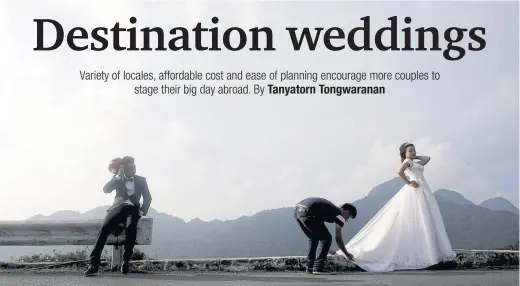  ??  ?? A photograph­er adjusts a bride’s dress as her groom looks on in the resort town of Tam Dao, north of Hanoi.