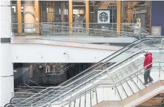  ?? RENÉ JOHNSTON TORONTO STAR FILE PHOTO ?? A person wearing protective mask walks the stairs in an empty Eaton Centre. Thousands of Canadians lost their jobs because of the pandemic and many find income aid a confusing process.