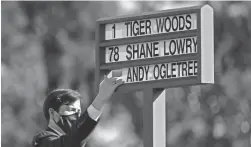  ??  ?? A staff member changes out the nameplates during the first round of the Masters at Augusta National on Thursday.